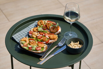 Italian bruschettas with shrimps, cherry tomatoes, lettuce and cashew nuts