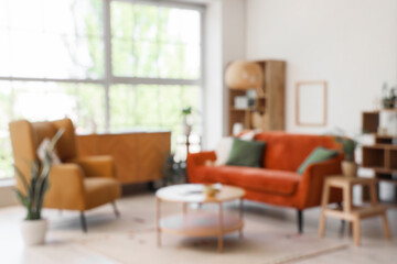 Armchair, sofa and coffee table in living room. Blurred view
