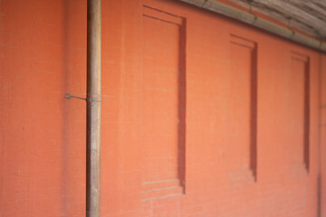 Rust red wall angled view with metal pipe background, selective focus, empty right side for copy space