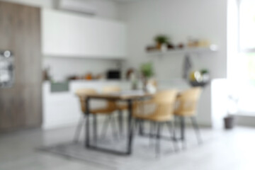 Blurred view of light kitchen with dining table and white counters