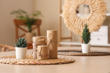Candles with plant on wooden table in dining room, closeup