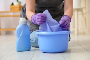 Female janitor soaking rag in water, closeup
