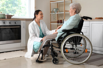 Physical therapist with senior woman in wheelchair holding hands at home