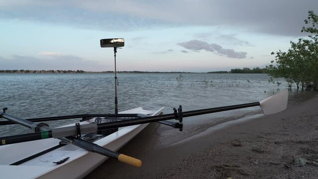 Rowing shell with hatchet oars and rowing mirror is wobbling on a shore of Boyd Lake, Colorado