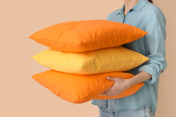 Woman with bright pillows on beige background, closeup