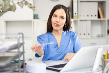 Woman physician sitting at table in her office and giving recipe.