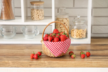 Wicker basket with tasty strawberries on wooden kitchen counter in kitchen