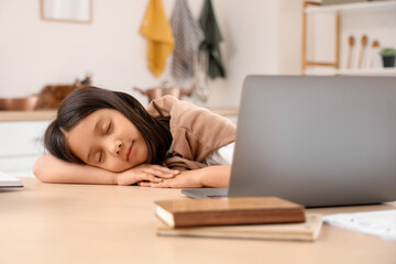 Tired little Asian girl with laptop sleeping at home