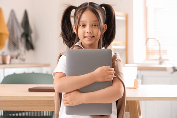 Little Asian girl with laptop in kitchen