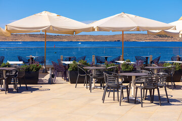 Outdoor restaurant with a sea view. Summer terrace with tables and chairs under white umbrellas
