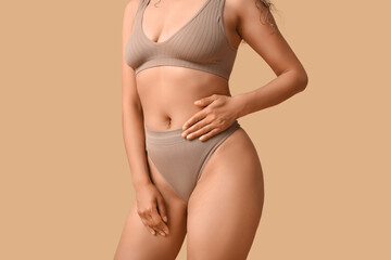 Beautiful young African-American woman in stylish underwear on beige background, closeup