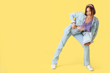 Fototapeta premium Beautiful young woman in stylish clothes on yellow background