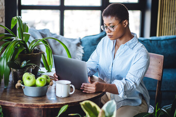 Young attractive African American woman nutritionist is working on laptop in a beautiful green...