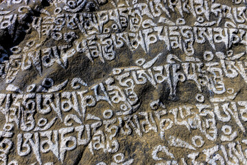 Nepal sacred stones mani with mantra written and carved on the surface. Prayer stones shire on the mountain trekking path on Everest Base Camp trek. Nepali buddhist mantra Om Mani Padme Hum on rock