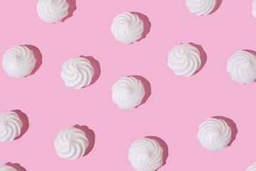 White meringue cookies on a bright pink background. Creative sweet delicacy pattern, dessert background.