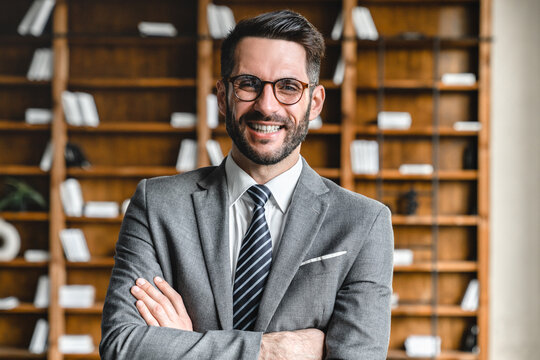 Closeup cropped portrait of young rich businessman in formal suit with arms crossed looking at the camera in modern office. Wealthy foreman manager working, making money at workplace