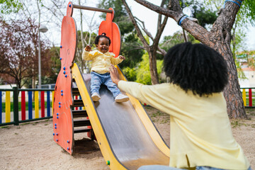 A woman is holding a child on a slide