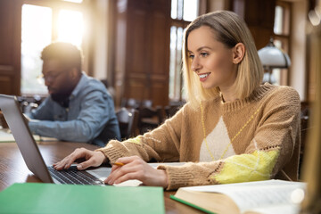 Blonde smiling woman at the laptop in the library
