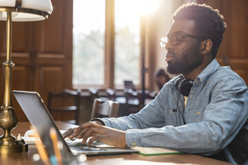 Dark-skinned young man sitting at the laptop in the library