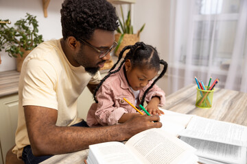 Happy father helping schoolgirl daughter studying