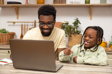 African American father helps his daughter with lessons during distance education