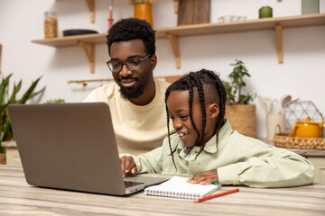 African American father helps his daughter with lessons during distance education