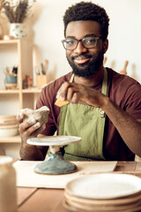 Man in apron working in the pottery studio and looking involved