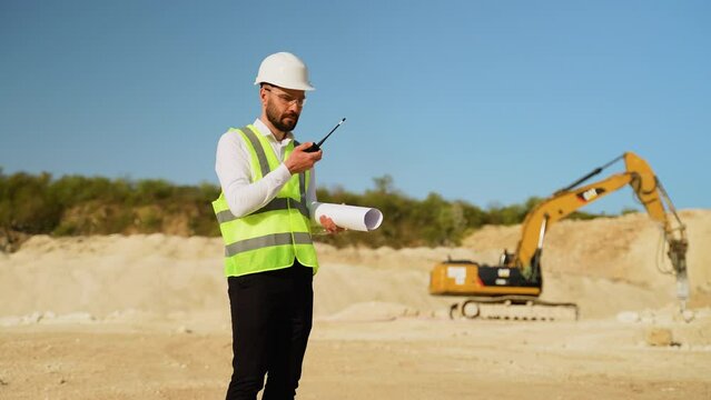 Foreman giving commands to employees using walkie talkie at quarry