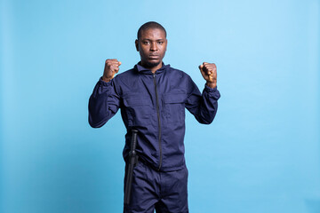 Confident security guard is clenching his fists in front of the camera, prepared for a fight in...