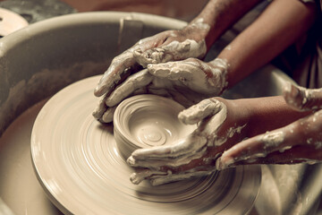 Close up picture of hands working with wet clay and molding its shape