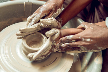 Hands of two people making a new pottery product together