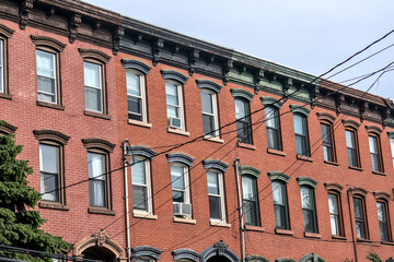 jersey city brownstone building detail (historic pre-war red brick buildings with power lines) beautiful real estate apartment homes with cornice decor urban city life window detail close up family © Yuriy T