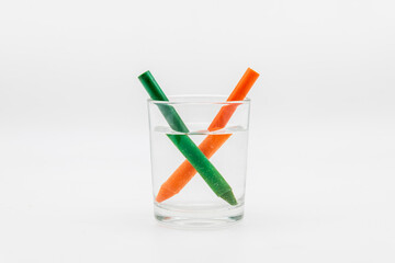 Refracción de la luz, demostrada con un vaso lleno de agua con lápices de colores	