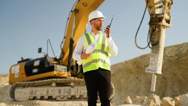 Foreman giving commands to employee in drilling machine using walkie talkie at stone quarry
