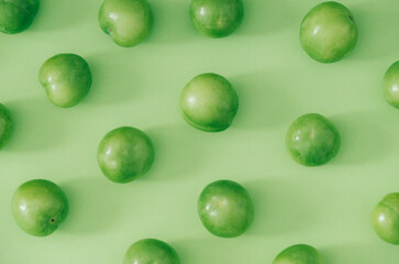 Trendy fruit pattern made of fresh green plums on light pastel green background. Minimal layout. Nature summer concept.