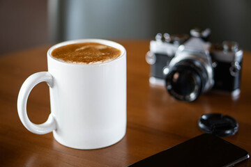 Vintage film camera and coffee mug on a wooden table