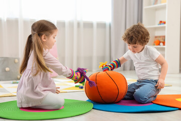 Cute little children playing with funny sock puppets and soft toy ball in kindergarten