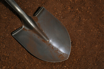 Metal shovel on fertile soil, top view. Gardening tool