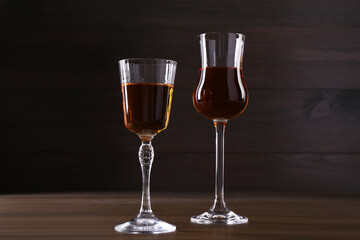 Different delicious liqueurs in glasses on wooden table
