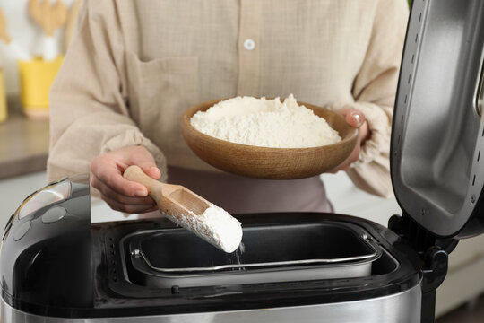 Making dough. Woman adding flour into breadmaker machine, closeup