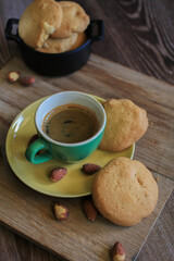 Coffee in green cup with cookies on the wooden table. Rustic wooden background. Cozy morning Breakfast at home or in a cafe.