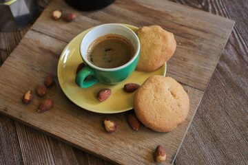 Coffee in green cup with cookies on the wooden table. Rustic wooden background. Cozy morning Breakfast at home or in a cafe.