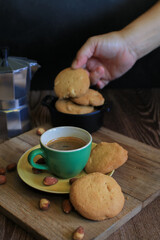 Coffee in green cup with cookies on the wooden table. Rustic wooden background. Cozy morning Breakfast at home or in a cafe.