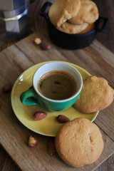 Coffee in green cup with cookies on the wooden table. Rustic wooden background. Cozy morning Breakfast at home or in a cafe.