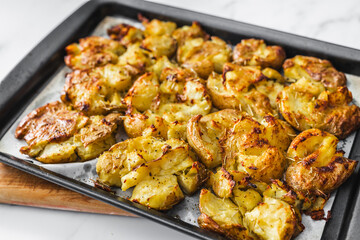 smashed baby potatoes on oven tray with rosemary and herbs