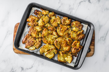 smashed baby potatoes on oven tray with rosemary and herbs