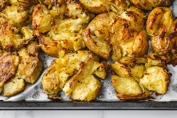 smashed baby potatoes on oven tray with rosemary and herbs