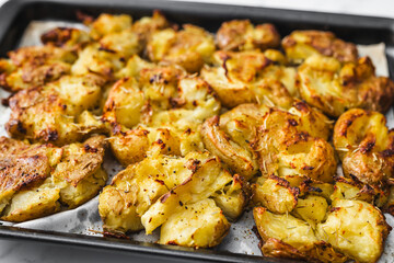 smashed baby potatoes on oven tray with rosemary and herbs