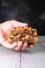 Hand holding split NY Style homemade chocolate chip cookie