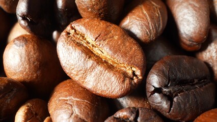 The world of coffee with close-up of glossy, dark brown beans. Their intricate texture and visible cracks speak volumes of a meticulous roasting process, promising a deeply satisfying cup.
